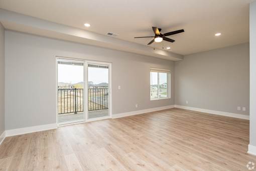 A room with a ceiling fan and sliding glass doors.