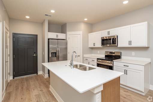 A modern kitchen with white countertops and stainless steel appliances.