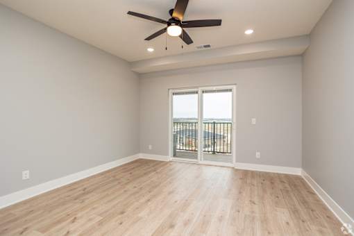 A room with a ceiling fan and sliding glass doors.