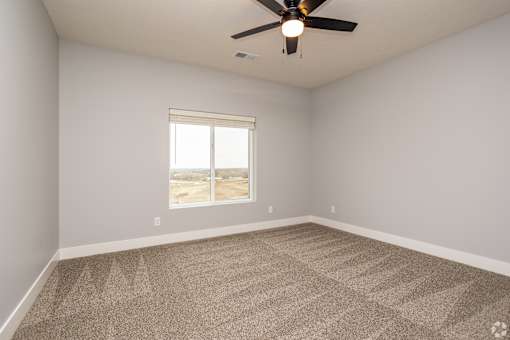 A room with a ceiling fan and a window overlooking a desert landscape.