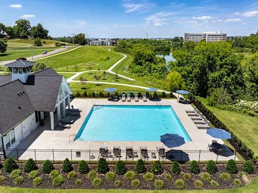 A large swimming pool surrounded by a fence and a building in the background.
