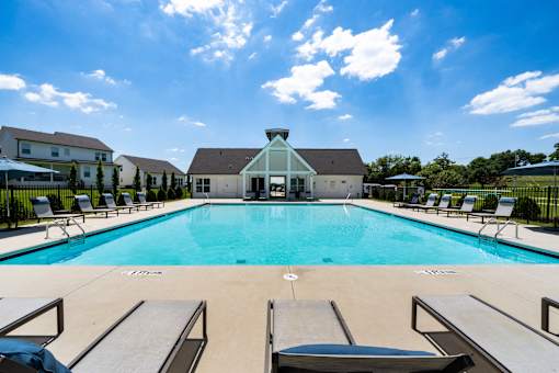 A swimming pool with lounge chairs and a building in the background.