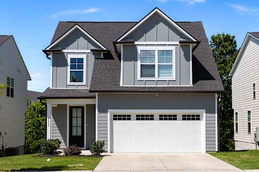 A two-story house with a garage door and a window on the second floor.