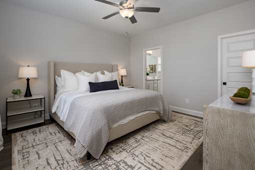 A bedroom with a large bed and a ceiling fan.
