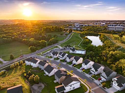 A sunset view of a residential area with houses and a park.