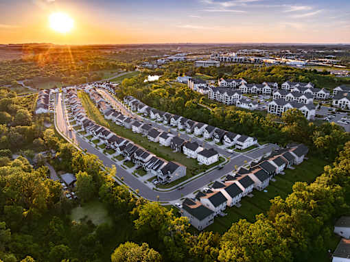 A sunset view of a residential area with houses and trees.
