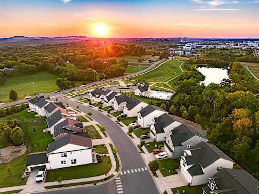 A sunset view of a residential neighborhood with houses and a lake.