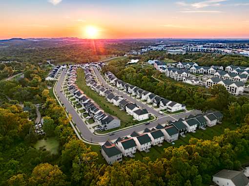 A sunset view of a residential area with houses and trees.