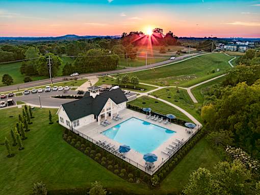 A house with a pool surrounded by a green lawn.