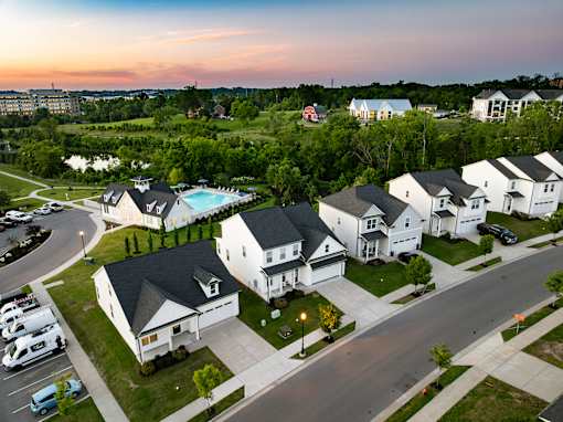 A sunset view of a neighborhood with houses and a pool.