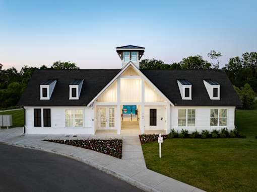 A white house with a black roof and a tower on top.
