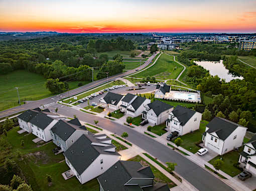 A sunset view of a residential area with houses and a river.