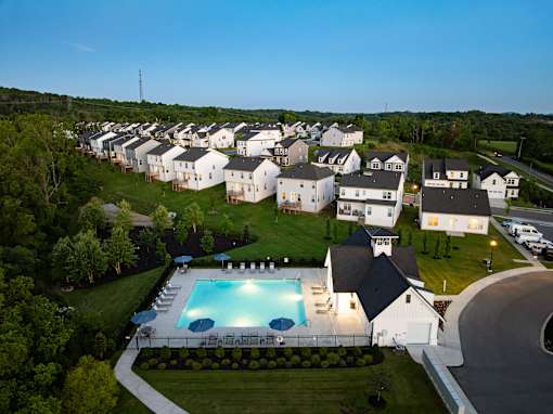 A swimming pool is surrounded by a grassy area and a white building.