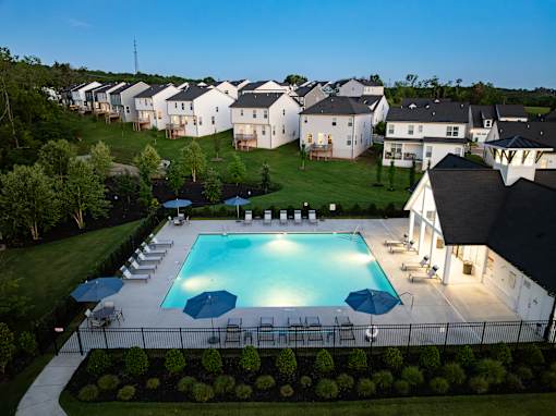 A swimming pool surrounded by a black fence and several chairs.