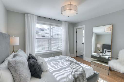A bedroom with a large bed and a mirror on the wall.