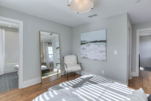 A bedroom with a large bed, a chair, and a painting on the wall.