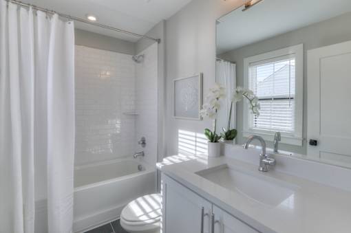 A white bathroom with a toilet, sink, and shower.