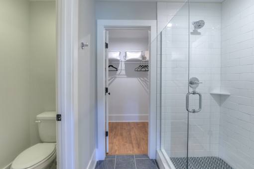 A white bathroom with a toilet and a walk in shower.