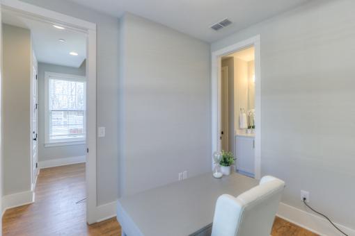A white chair is in a white room with a table and a plant.