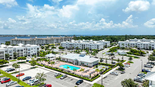 A large white resort with a pool and a parking lot.