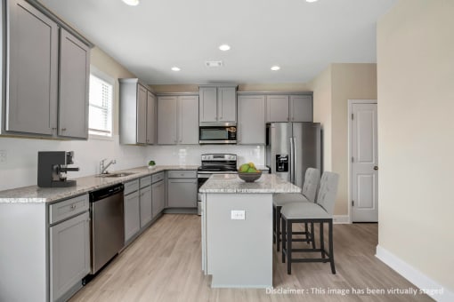 a kitchen with gray cabinets and stainless steel appliances and an island with white counter tops