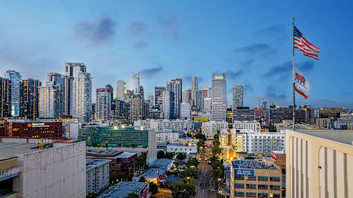A cityscape with a prominent American flag flying in the foreground.