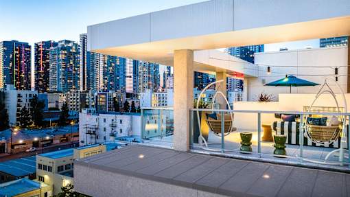 A rooftop patio with a white pergola and outdoor furniture.
