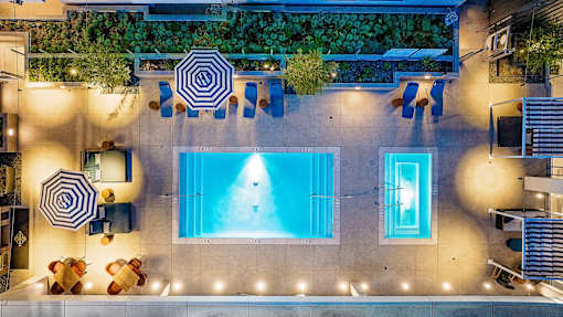 A swimming pool surrounded by a patio with chairs and tables.
