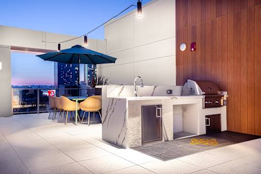 A modern outdoor kitchen area with a bar and chairs.