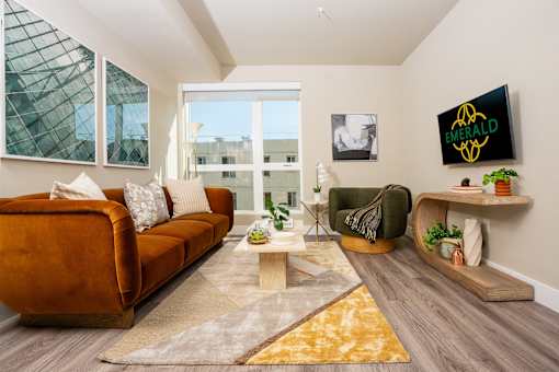 A living room with a brown couch, a green chair, and a yellow rug.
