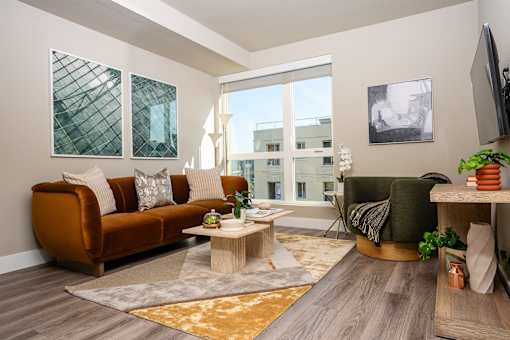A living room with a brown sofa, a coffee table, and a flat screen TV mounted on the wall.