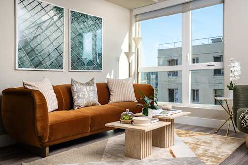 A living room with a brown couch, a coffee table, and a large window.