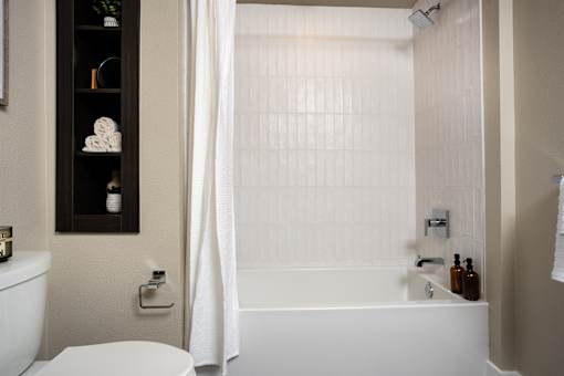 A white bathroom with a toilet, a bathtub, and a shower curtain.