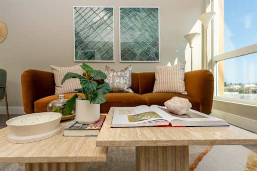 A living room with a brown sofa, a wooden coffee table, and a large window.