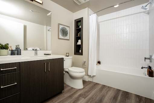 A modern bathroom with a white tub and wooden floors.