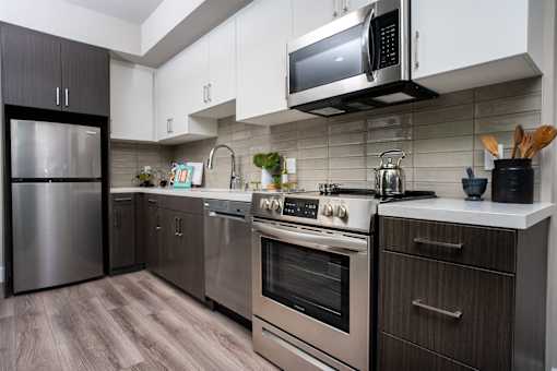 A modern kitchen with stainless steel appliances and wooden flooring.