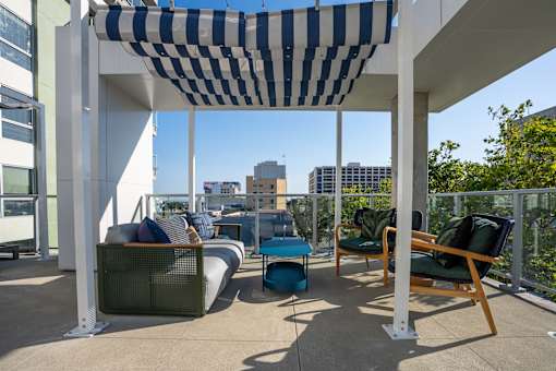 A patio with a striped awning and a blue chair.