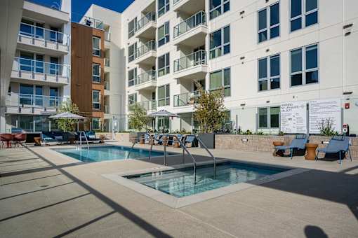 A pool area with a slide and loungers in front of apartment buildings.