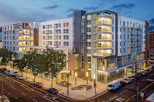 A modern apartment building with a parking lot in front.