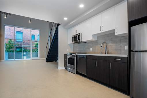 A modern kitchen with black cabinets and stainless steel appliances.