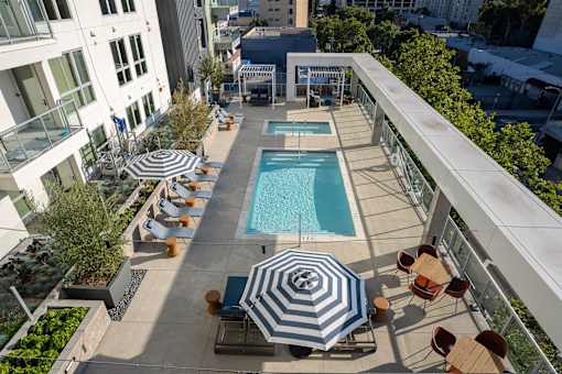 A pool surrounded by chairs and umbrellas on a patio.