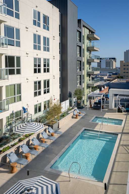 A rooftop pool area with sun loungers and a striped rug.