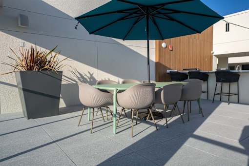 A table with chairs and an umbrella is on a patio.
