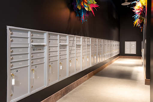 A row of white mailboxes are lined up on a wall.