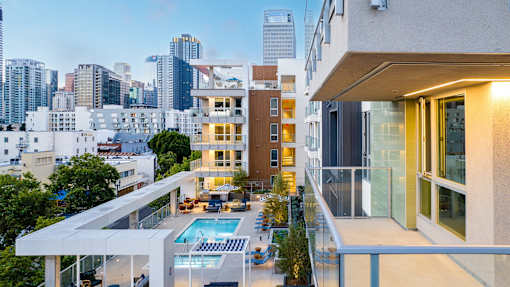 A modern apartment building with a pool in the foreground.