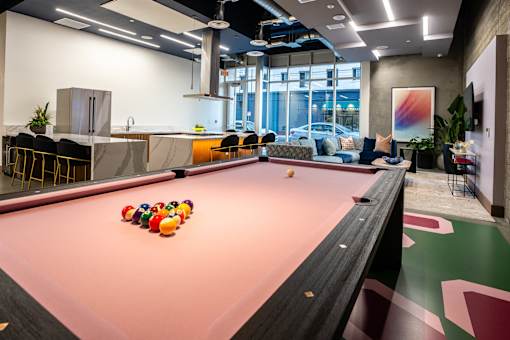 A pool table with a pink cloth and several balls on it.
