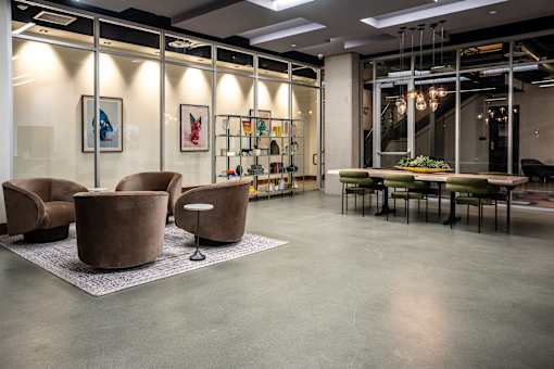 A modern office space with brown leather chairs and a glass wall.