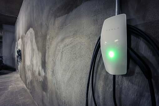 A Tesla charging station is lit up green.