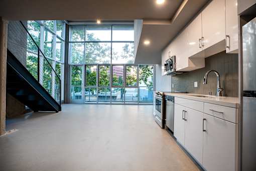 A modern kitchen with a staircase on the left side.