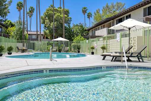 A pool with a waterfall and a bench.